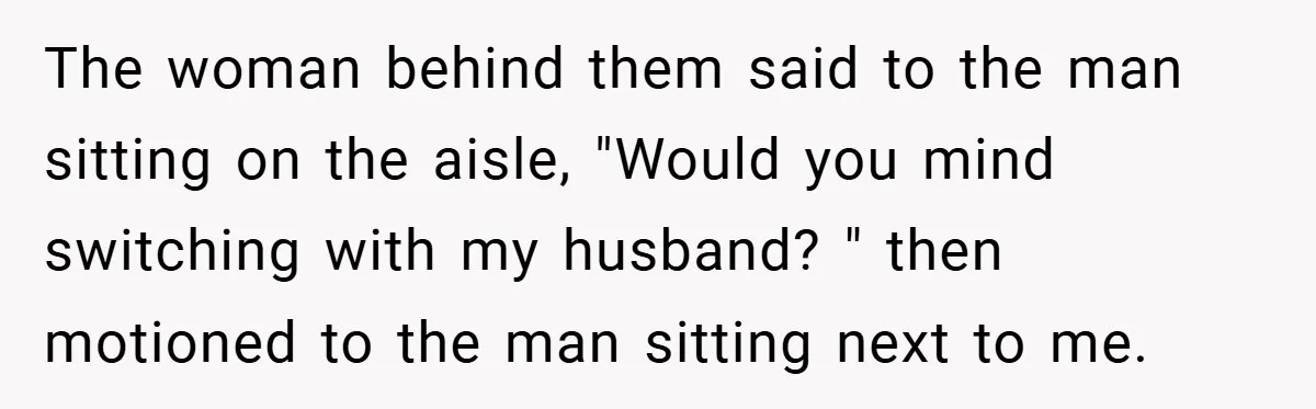 The woman behind them said to the man sitting on the aisle, "Would you mind switching with my husband? " then motioned to the man sitting next to me.