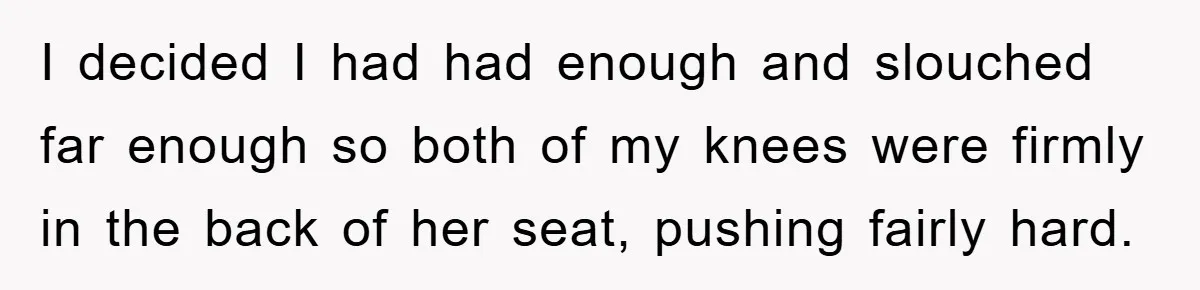 I decided I had had enough and slouched far enough so both of my knees were firmly in the back of her seat, pushing fairly hard.