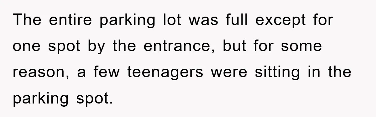 The entire parking lot was full except for one spot by the entrance, but for some reason, a few teenagers were sitting in the parking spot.