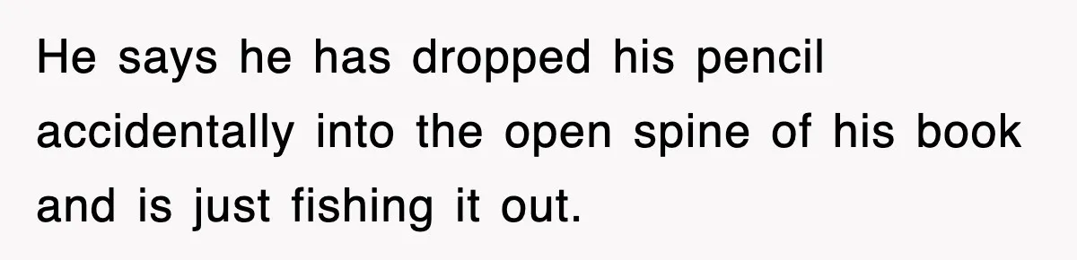 He says he has dropped his pencil accidentally into the open spine of his book and is just fishing it out.