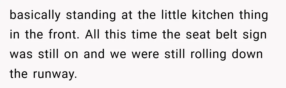 basically standing at the little kitchen thing in the front. All this time the seat belt sign was still on and we were still rolling down the runway.