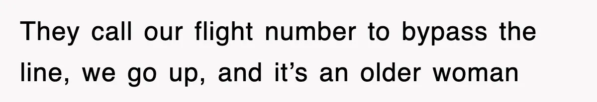 They call our flight number to bypass the line, we go up, and it’s an older woman