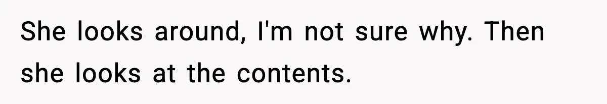 She looks around, I'm not sure why. Then she looks at the contents.