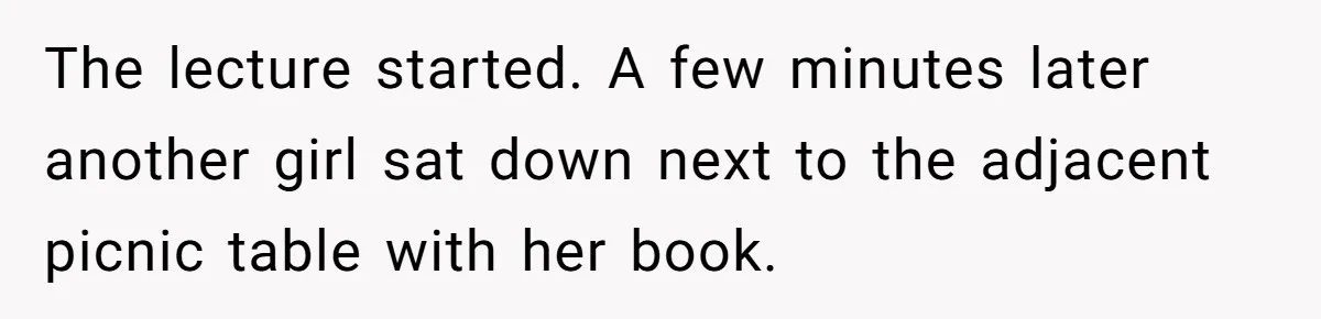The lecture started. A few minutes later another girl sat down next to the adjacent picnic table with her book.