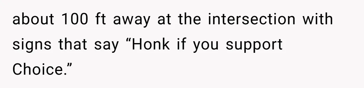 about 100 ft away at the intersection with signs that say “Honk if you support Choice.”
