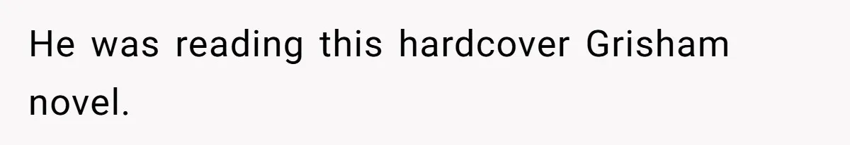 He was reading this hardcover Grisham novel.