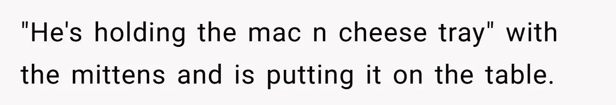 "He's holding the mac n cheese tray" with the mittens and is putting it on the table.