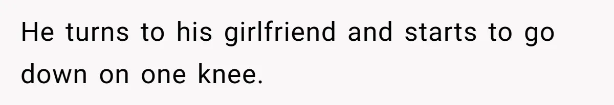 He turns to his girlfriend and starts to go down on one knee.