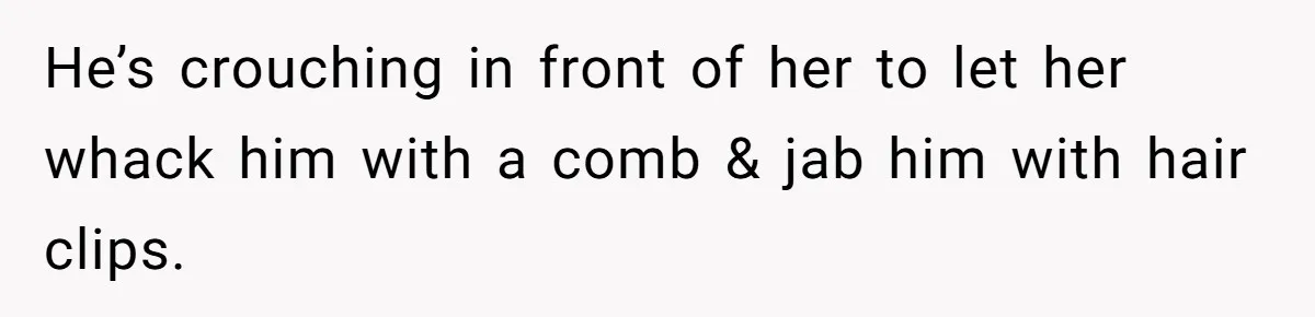 He’s crouching in front of her to let her whack him with a comb & jab him with hair clips.
