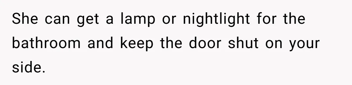She can get a lamp or nightlight for the bathroom and keep the door shut on your side.