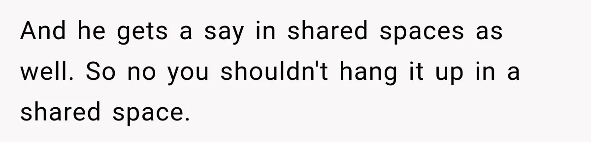 And he gets a say in shared spaces as well. So no you shouldn't hang it up in a shared space.