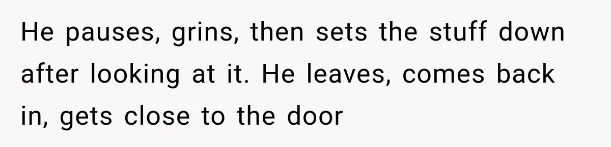He pauses, grins, then sets the stuff down after looking at it. He leaves, comes back in, gets close to the door