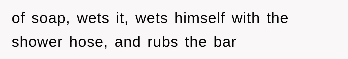 of soap, wets it, wets himself with the shower hose, and rubs the bar