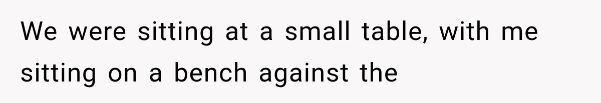 We were sitting at a small table, with me sitting on a bench against the