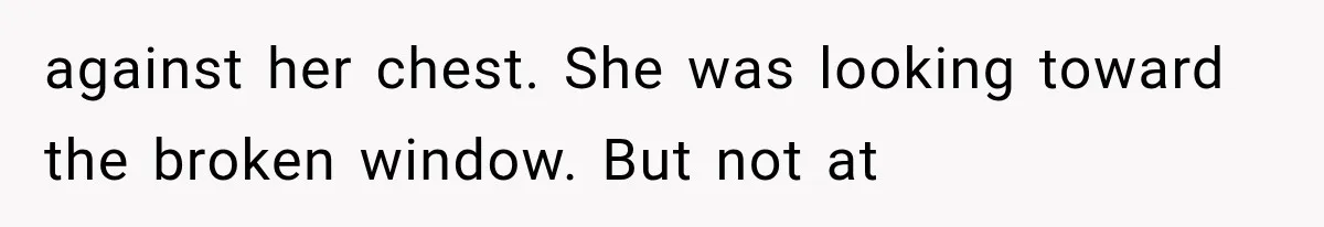 against her chest. She was looking toward the broken window. But not at